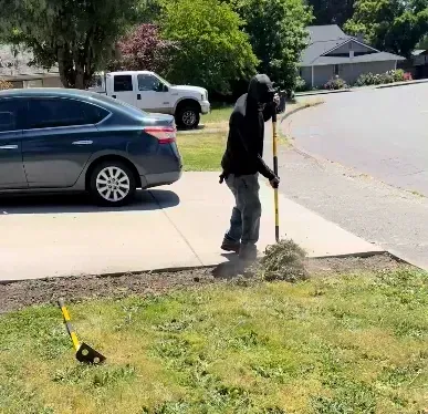 A lawn care professional removing a shrub from a residential property in Washington County, OR