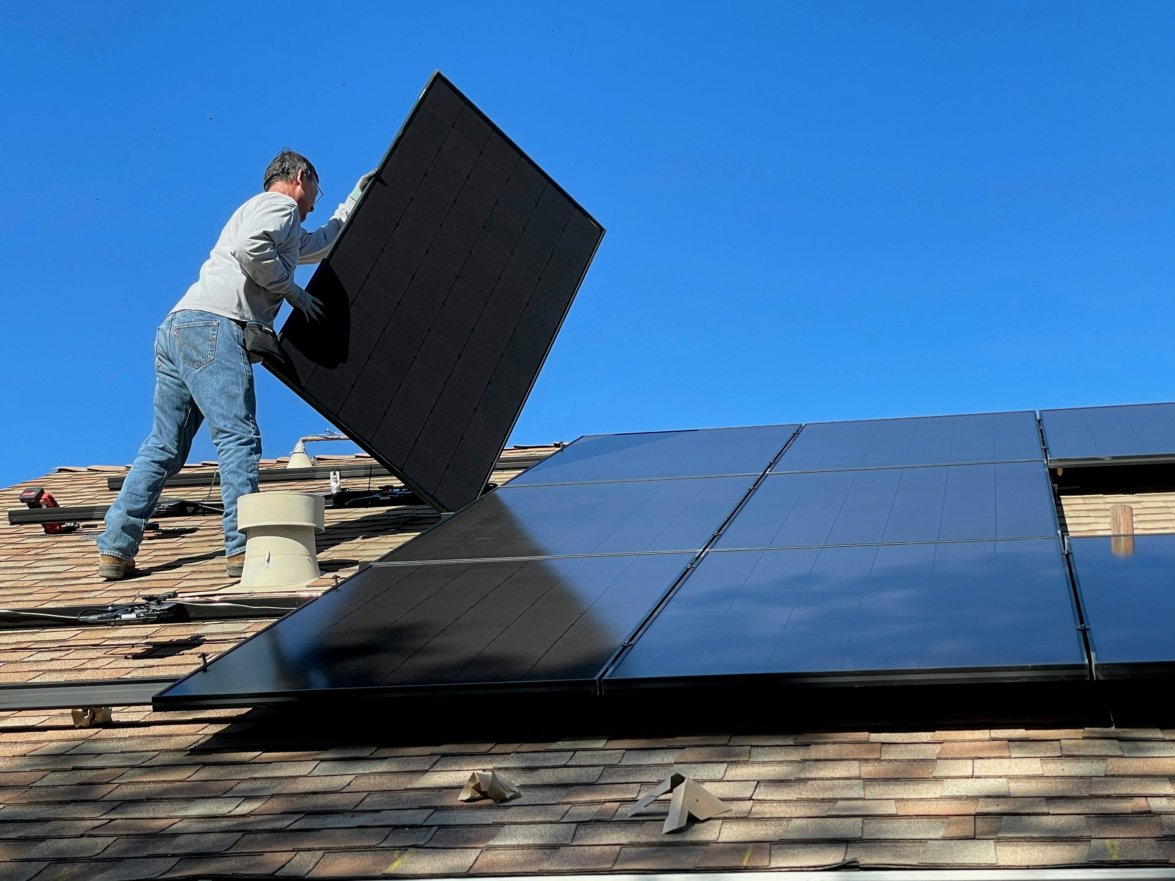 a man moving solar panels on a roof